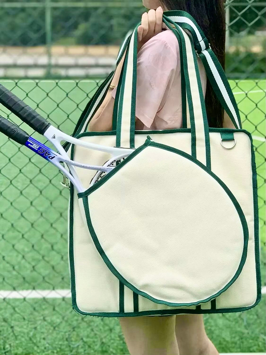 A vintage-inspired tennis tote bag for women, featuring an attached front racket case, an adjustable crossbody strap, and a crisp white design with classic green stripes.