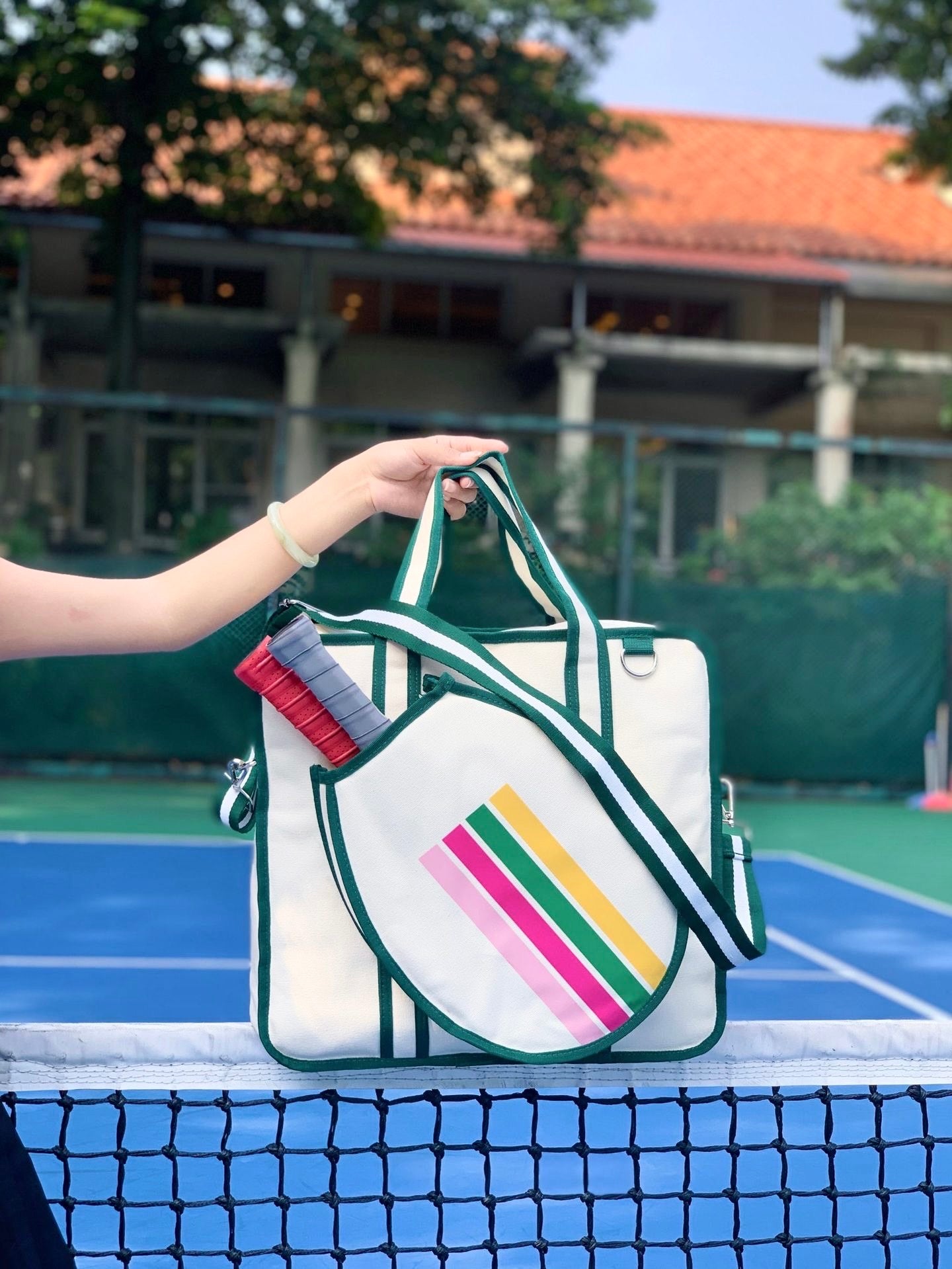 A vintage-inspired tennis tote bag for women, featuring an attached front racket case, an adjustable crossbody strap, and a crisp white design with classic stripes yellow,pink and green.