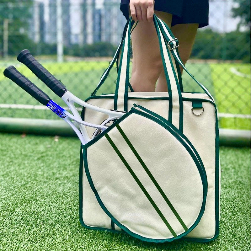 A vintage-inspired tennis tote bag for women, featuring an attached front racket case, an adjustable crossbody strap, and a crisp white design with classic green stripes.